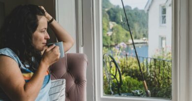 Nachdenkliche Frau mit Tasse am Fenster