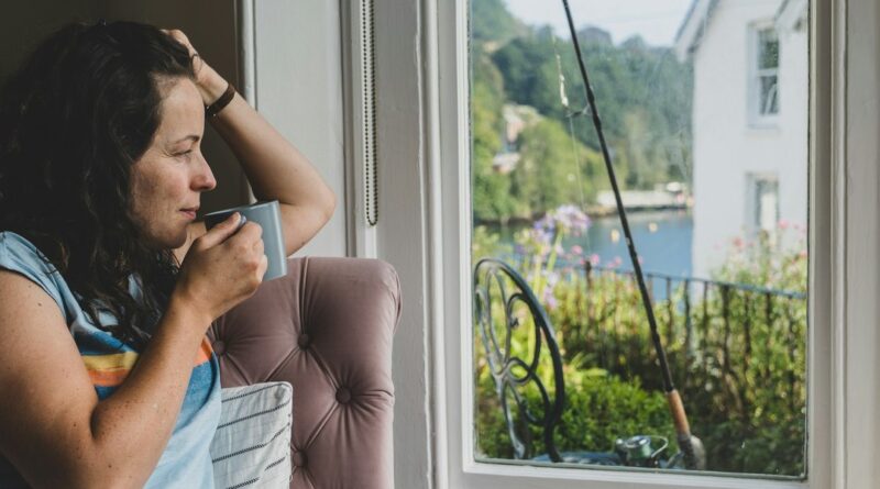 Nachdenkliche Frau mit Tasse am Fenster