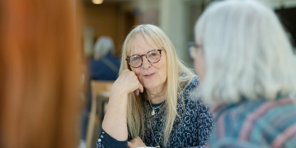 Zwei Frauen im Gespräch an einem Café-Tisch, eine hört aufmerksam zu